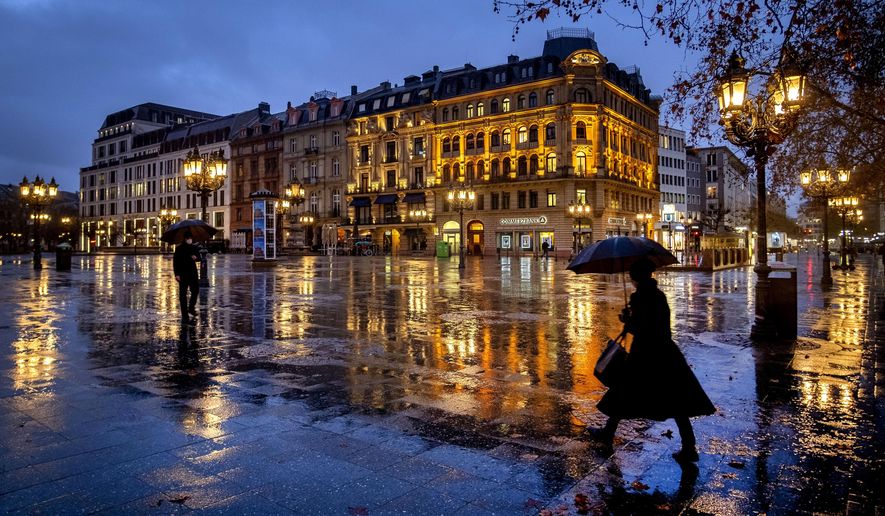 People under umbrellas on the square in front of the Old Opera in Frankfurt, Germany, on a rainy Friday morning, Jan. 22, 2021. (AP Photo/Michael Probst)