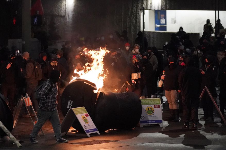 A trash can burns as people take part in a protest against police brutality, late Sunday, Jan. 24, 2021, in downtown Tacoma, Wash., south of Seattle. The protest came a day after at least two people were injured when a Tacoma Police officer responding to a report of a street race drove his car through a crowd of pedestrians that had gathered around him. Several people were knocked to the ground and at least one person was run over. (AP Photo/Ted S. Warren)