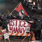 In this file photo, a protester carries a flag that reads &#39;Antifascist Action&#39; near a banner that reads &#39;ustice for Manny,&#39; during a protest against police brutality, late Sunday, Jan. 24, 2021, in downtown Tacoma, Wash., south of Seattle. (AP Photo/Ted S. Warren) **FILE**