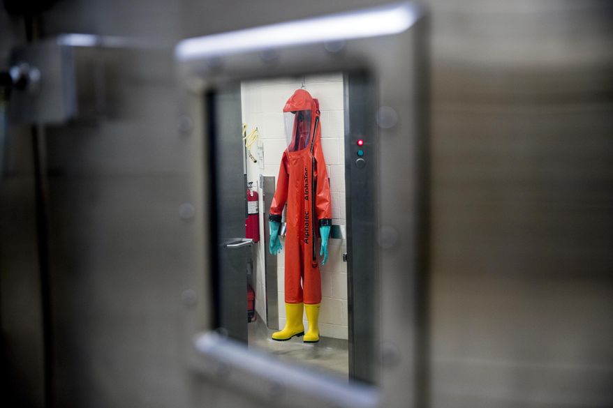 In this March 19, 2020, file photo, a biosafety protective suit for handling viral diseases are hung up in a biosafety level 4 training facility at U.S. Army Medical Research and Development Command at Fort Detrick in Frederick, Md., where scientists are working to help develop solutions to prevent, detect and treat the coronavirus. China is trying to spread doubt about the effectiveness of Western vaccines and the origin of the coronavirus as a World Health Organization-selected team of scientists are in the city where the pandemic first broke out. (AP Photo/Andrew Harnik, File)