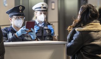 Officers of the German Federal Police check passengers arriving with a plane from Prague at the Frankfurt Airport in Frankfurt, Germany, Sunday, Jan 24, 2021. Anyone how is entering Germany from countries classify as high-risk countries by the federal government, must now be able to show a negative, up-to-date Corona test. (Boris Roessler/dpa via AP)