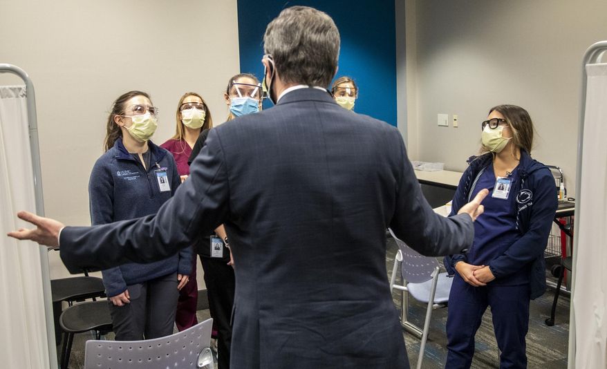 North Carolina Gov. Roy Cooper thanks physician assistant students while touring a large-scale vaccination site at UNC's Friday Center in Chapel Hill Tuesday, Jan. 19 2021. UNC Hospitals hope to administer 2500 first COVID-19 vaccine doses at the Friday Center by the end of this week. (Travis Long/The News & Observer via AP)