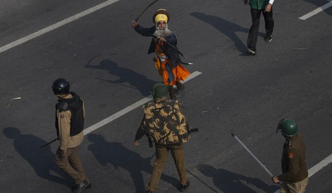 FILE - A Nihang, or a Sikh warrior, brandishes a sword at policemen as protesting farmers march to the capital breaking police barricades during India&#x27;s Republic Day celebrations in New Delhi, India, Tuesday, Jan.26, 2021. (AP Photo/Altaf Qadri)