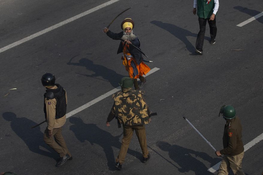 FILE - A Nihang, or a Sikh warrior, brandishes a sword at policemen as protesting farmers march to the capital breaking police barricades during India's Republic Day celebrations in New Delhi, India, Tuesday, Jan.26, 2021. (AP Photo/Altaf Qadri)