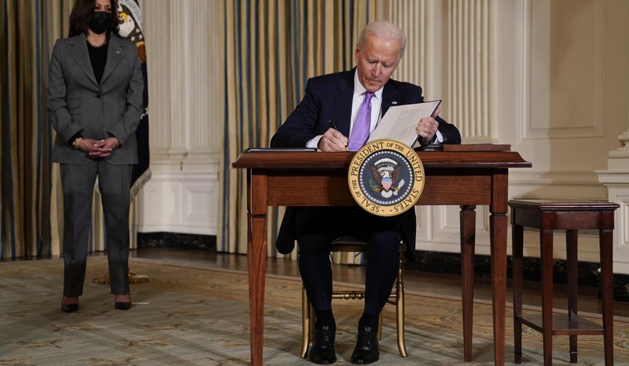 President Joe Biden signs executive orders in the State Dining Room of the White House, Tuesday, Jan. 26, 2021, in Washington. Vice President Kamala Harris listens at left. (AP Photo/Evan Vucci)