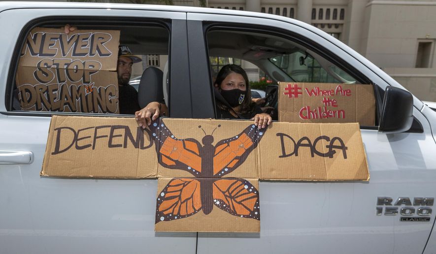 In this June 18, 2020, file photo, people hold signs during a vehicle caravan rally to support the Deferred Action for Childhood Arrivals program (DACA), around MacArthur Park in Los Angeles. (AP Photo/Damian Dovarganes, File)