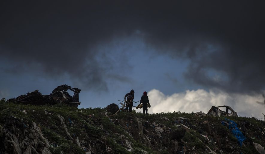 Two Palestinian boys play on top of piles of garbage on a rainy day in a poor neighbourhood of Khan Younis, in the southern Gaza Strip, Wednesday, Jan. 20, 2021. (AP Photo/Khalil Hamra)