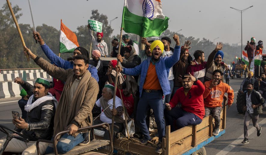 Protesting farmers riding tractors shout slogans as they march to the capital breaking police barricades during India's Republic Day celebrations in New Delhi, India, Tuesday, Jan. 26, 2021. Tens of thousands of farmers drove a convoy of tractors into the Indian capital as the nation celebrated Republic Day on Tuesday in the backdrop of agricultural protests that have grown into a rebellion and rattled the government. (AP Photo/Altaf Qadri)
