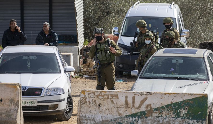 Israeli soldiers secure the area where the military said troops killed a Palestinian man suspected of trying to attack soldiers, at a West Bank junction near the joint Israeli-Palestinian industrial zone of Barkan, Tuesday, Jan. 26, 2021. (AP Photo/Ariel Schalit)