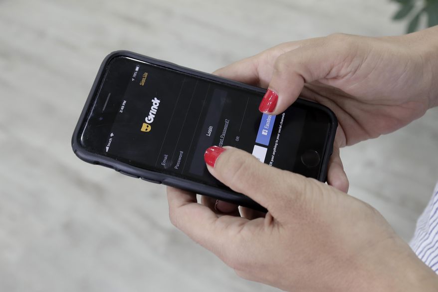 FILE - In this Wednesday, May 29, 2019 file photo, a woman checks the Grindr app on her mobile phone in Beirut, Lebanon. Norway is fining gay dating app Grindr $11.7 million under for failing to get consent from users before sharing their personal information with advertising companies, in breach of stringent European Union privacy rules. Norwegian's data privacy watchdog said Tuesday, Jan. 26, 2021 that it notified the company of its draft decision to issue a fine for 100 million Norwegian krone, equal to 10% of its annual global revenue. (AP Photo/Hassan Ammar, file)