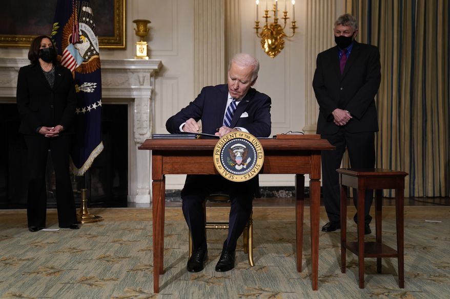 President Joe Biden signs an executive order on climate change, in the State Dining Room of the White House, Wednesday, Jan. 27, 2021, in Washington. Vice President Kamala Harris looks on at left. (AP Photo/Evan Vucci)