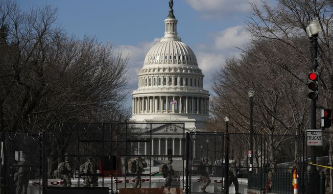 National Guard troops walk outside the Capitol as the security perimeter continues to shrink and many Guard units head home, two days after the inauguration of President Joe Biden on Friday, Jan. 22, 2021 in Washington.(AP Photo/Rebecca Blackwell)