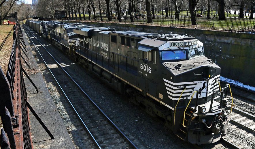 FILE- In this March 26, 2018, file photo, a Norfolk Southern freight train rolls through downtown Pittsburgh. Norfolk Southern’s fourth-quarter profit improved slightly even though it hauled 1% less freight because the railroad controlled expenses tightly as the economy continued to slowly recover from last year’s widespread shutdowns during the coronavirus pandemic.  (AP Photo/Gene J. Puskar, File)