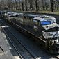 FILE- In this March 26, 2018, file photo, a Norfolk Southern freight train rolls through downtown Pittsburgh. Norfolk Southern’s fourth-quarter profit improved slightly even though it hauled 1% less freight because the railroad controlled expenses tightly as the economy continued to slowly recover from last year’s widespread shutdowns during the coronavirus pandemic.  (AP Photo/Gene J. Puskar, File)