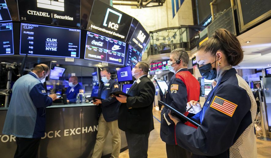 In this photo provided by the New York Stock Exchange, trader Samantha Tavares, right, works with colleagues on the floor, Wednesday, Jan. 27, 2021. Stocks were broadly lower in afternoon trading Wednesday, as investors focus on the outlook for the economy and corporate profits amid a still-raging coronavirus pandemic. (Courtney Crow/New York Stock Exchange via AP)