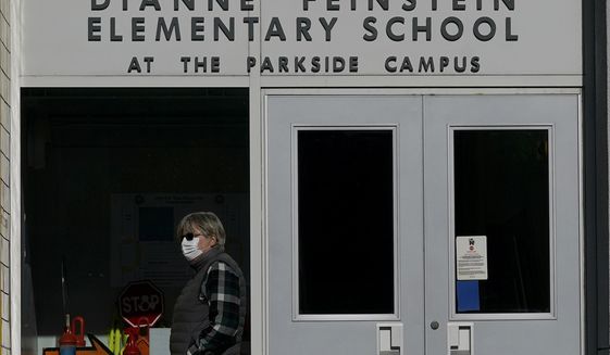 A pedestrian walks below a sign for Dianne Feinstein Elementary School in San Francisco, on Dec. 17, 2020. The San Francisco school board has voted to remove the names of George Washington and Abraham Lincoln from public schools after officials deemed them and other prominent figures, including Sen. Dianne Feinstein unworthy of the honor. After months of controversy, the board voted 6-1 Tuesday, Jan. 26, 2021, in favor of renaming 44 San Francisco school sites with new names with no connection to slavery, oppression, racism or similar criteria, the San Francisco Chronicle reported. (AP Photo/Jeff Chiu)