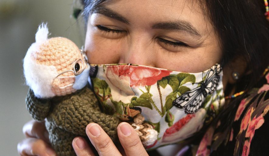 Tobey King, of Corpus Christi, Texas, embraces the crochet Bernie Sanders doll that she made and sold on eBay for $20,300 on Tuesday, Jan. 26, 2021. All of the proceeds are being donated to Meals on Wheels. (Billy Calzada/The San Antonio Express-News via AP)