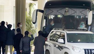 Workers wave to the team of experts from the World Health Organization who ended their quarantine and prepare to leave the quarantine hotel by bus in Wuhan in central China&#39;s Hubei province on Thursday, Jan. 28, 2021. (AP Photo/Ng Han Guan)