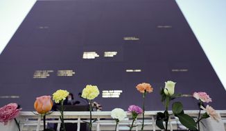 Flowers line the railing placed their by visitors at the Space Mirror Memorial during a ceremony to honor fallen astronauts at the Kennedy Space Center Visitors Complex, Thursday, Jan. 28, 2021, in Cape Canaveral, Fla. The memorial displays the names of astronauts that lost their lives furthering the cause of space exploration. (AP Photo/John Raoux)