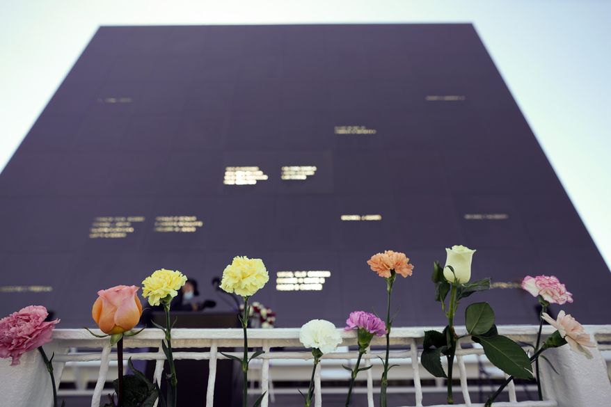 Flowers line the railing placed their by visitors at the Space Mirror Memorial during a ceremony to honor fallen astronauts at the Kennedy Space Center Visitors Complex, Thursday, Jan. 28, 2021, in Cape Canaveral, Fla. The memorial displays the names of astronauts that lost their lives furthering the cause of space exploration. (AP Photo/John Raoux)