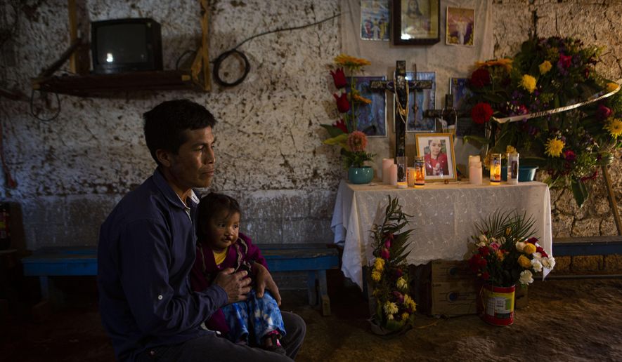 Ricardo Garcia and daughter Angela sit next to an altar adorned with photographs of his older daughter Santa Garcia, in his home in Comitancillo, Guatemala, Wednesday, Jan. 27, 2021. He believes his daughter Santa is one of the charred corpses found in a northern Mexico border state on Saturday. The country's Foreign Ministry said it was collecting DNA samples from a dozen relatives to see if there was a match with any of the bodies. (AP Photo/Oliver de Ros)