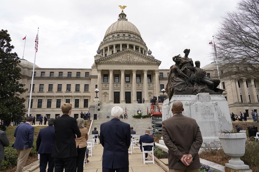 A sparse crowd of lawmakers, lobbyists and security, listen as Mississippi Republican Gov. Tate Reeves speaks about his policy priorities and the state's coronavirus pandemic response during his State of the State speech on Tuesday, Jan. 26, 2021, on the south steps of the state Capitol in Jackson, Miss. Reeves requested the outdoor venue and a limited number of attendees following covid protocol. (AP Photo/Rogelio V. Solis)
