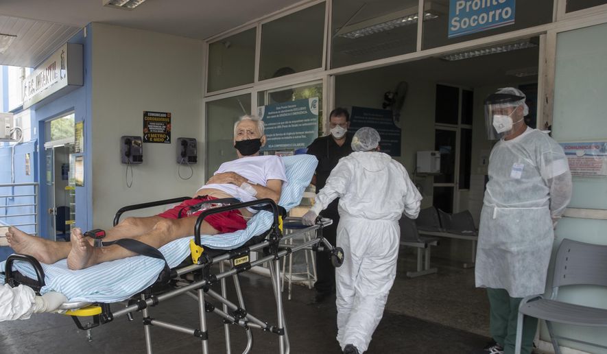 Health workers pull a COVID-19 patient from an ambulance into Santa Casa Hospital in Jau, Brazil, Thursday, Jan. 28, 2021. The Santa Casa hospital is operating at full capacity and patients take turns receiving oxygen. (AP Photo/Andre Penner)