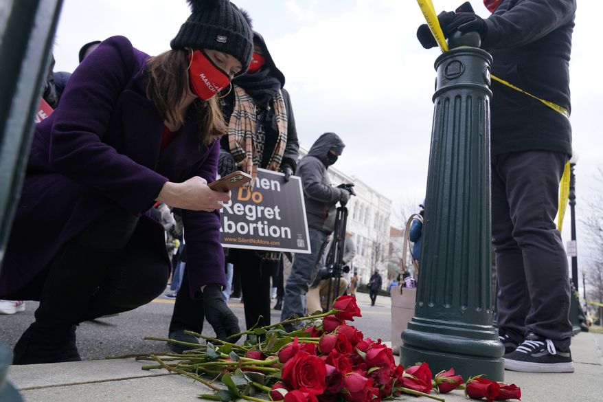 Catherine Glenn Foster, President and Chief Executive Officer of Americans United for Life, left, places a rose on the sidewalk on the back side of the Supreme Court during the 48th Annual March for Life in Washington, Friday, Jan. 29, 2021. (AP Photo/Susan Walsh)