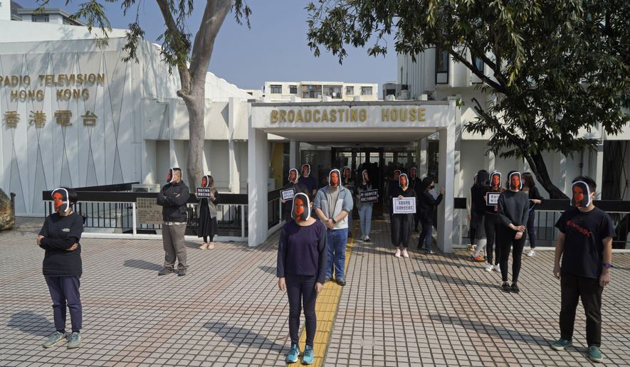Hong Kong public broadcaster RTHK staffers wear masks of resembling journalist Nabela Qoser during a silent protest against the management's treatment of Qoser outside Broadcasting House, in Hong Kong, Thursday, Jan. 28, 2021. Qoser is known for her tough questioning of Hong Kong government officials during the unrest of 2019. (AP Photo/Kin Cheung)