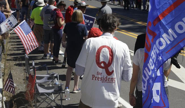 In this Aug. 20, 2020, file photo, a man in a QAnon T-shirt walks among Trump supporters as they wait for President Donald Trump to arrive and visit Mariotti Building Products in Old Forge, Pa. (AP Photo/Jacqueline Larma, File)