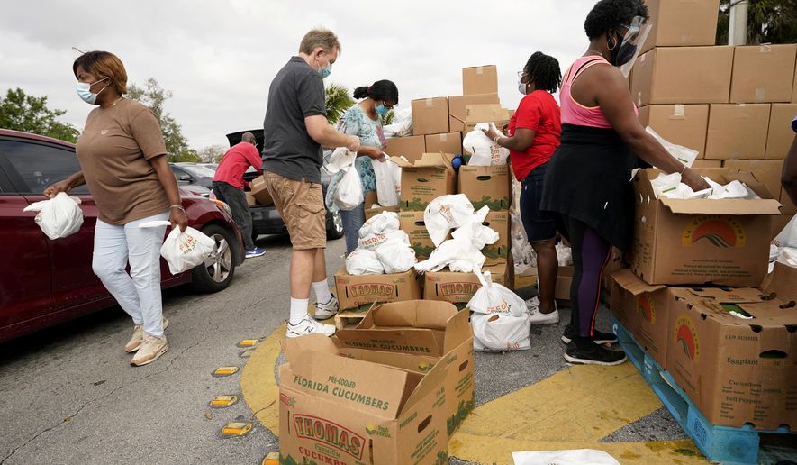 Volunteers load produce into bags as they work at a food distribution for local residents sponsored by Feeding South Florida, Thursday, Jan. 28, 2021, in Florida City, Fla. (AP Photo/Lynne Sladky)