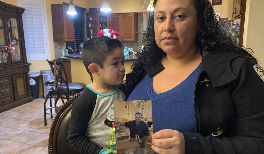 Nancy Espinoza, 37, sits with her 3-year-old son at their home in Corona, Calif., on Thursday, Jan. 28, 2021, while holding a photo of her husband Antonio Espinoza, who died of COVID-19 three days earlier. Espinoza said she never imagined the virus would take the life of her 36-year-old husband, who managed a hospice nurse program. (AP Photo/Eugene Garcia)