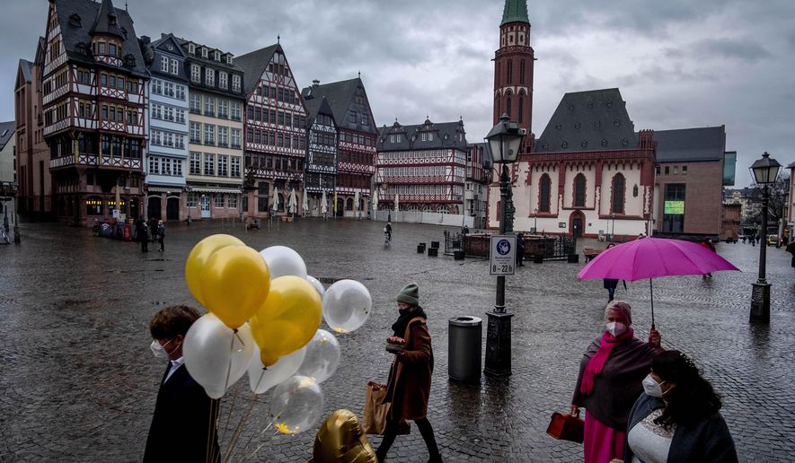 A bridal couple and friends walk over the Roemerberg square after their wedding in Frankfurt, Germany, Thursday, Jan. 28, 2021. Further restrictions to avoid the outspread of the coronavirus are discussed Thursday by the German government. (AP Photo/Michael Probst)