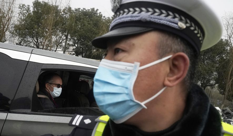Peter Ben Embarek of the World Health Organization team passes by a Chinese police officer as he leaves in a convoy from the Baishazhou wholesale market on the third day of field visit in Wuhan in central China&#x27;s Hubei province on Sunday, Jan. 31, 2021. (AP Photo/Ng Han Guan)