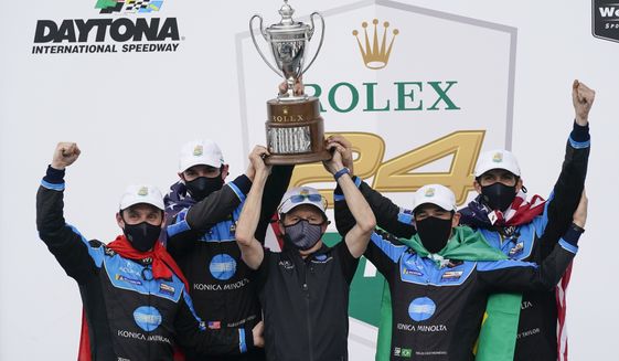 The Konica Minolta racing team, from left to right, Filipe Albuquerque, Alexander Rossi, team owner Wayne Taylor, Helio Castroneves and Ricky Taylor celebrate with the championship trophy after winning the Rolex 24 hour auto race at Daytona International Speedway, Sunday, Jan. 31, 2021, in Daytona Beach, Fla. (AP Photo/John Raoux)