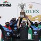 The Konica Minolta racing team, from left to right, Filipe Albuquerque, Alexander Rossi, team owner Wayne Taylor, Helio Castroneves and Ricky Taylor celebrate with the championship trophy after winning the Rolex 24 hour auto race at Daytona International Speedway, Sunday, Jan. 31, 2021, in Daytona Beach, Fla. (AP Photo/John Raoux)