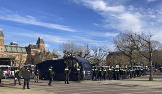 Dutch riot police line up in front of the Rijksmuseum, rear left, as they watch over a demonstration against the curfew and other COVID-19 related restrictions aimed at curbing the spread of the coronavirus, in Amsterdam, Netherlands, Sunday, Jan. 31, 2021. (AP Photo/Mike Corder)