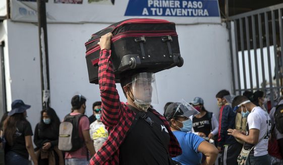 A passenger, wearing protective face gear amid the new coronavirus pandemic, arrives at a long-distance bus terminal, in Lima, Peru, Saturday, Jan. 30, 2021. Hundreds of people are traveling to their provinces of origin before a strict two-week quarantine begins Sunday in various regions of the country as a measure to curve the spread of COVID-19. (AP Photo/Rodrigo Abd)