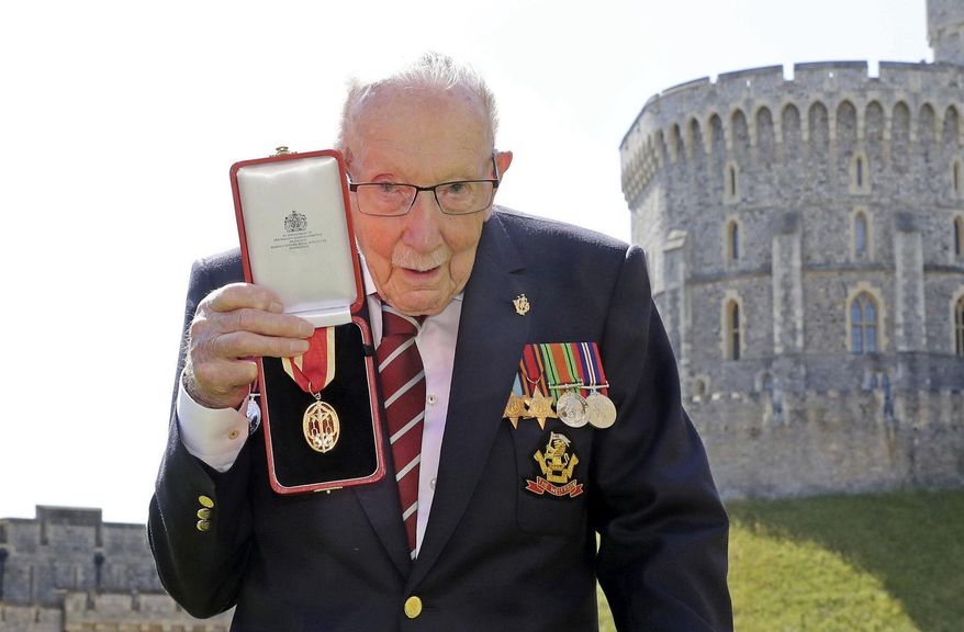 FILE - In this Friday, July 17, 2020 file photo, Captain Sir Thomas Moore poses for the media after receiving his knighthood from Britain's Queen Elizabeth, during a ceremony at Windsor Castle in Windsor, England. Tom Moore, the 100-year-old World War II veteran who captivated the British public in the early days of the coronavirus pandemic with his fundraising efforts, has been admitted to a hospital with COVID-19, his daughter said Sunday Jan. 31, 2021. (Chris Jackson/Pool Photo via AP, File)