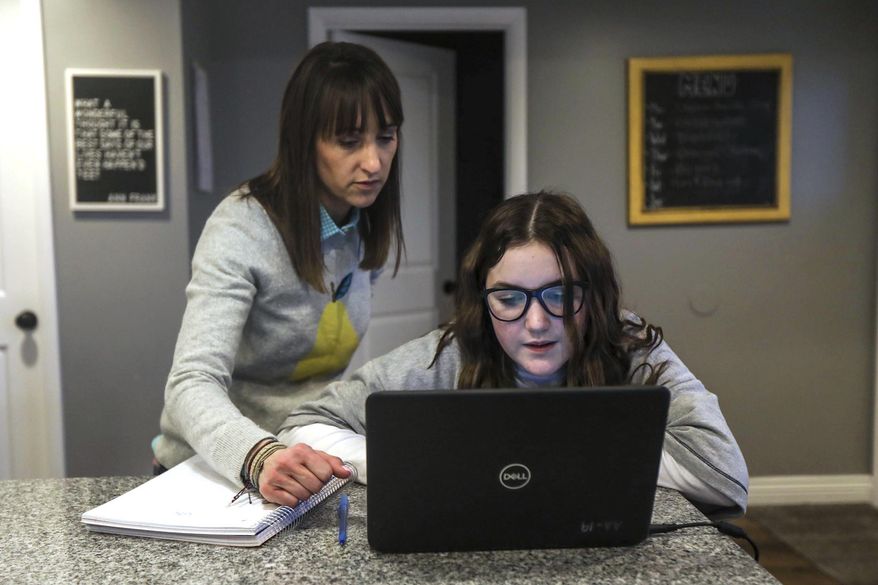 Kim Millard, left, helps daughter Molly with homework while dinner cooks in their home in Layton, Utah, on Thursday, Jan. 28, 2021. (Annie Barker/The Deseret News via AP)