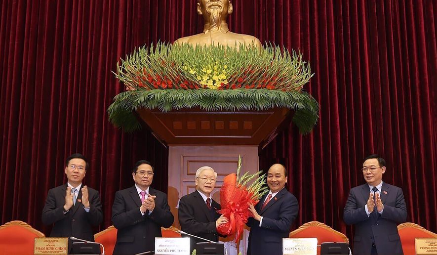Vietnam Communist party General Secretary Nguyen Phu Trong, center left, is presented with a bouquet by Prime Minister Nguyen Xuan Phuc, center right, in Hanoi, Vietnam, Sunday, Jan. 31, 2021. Vietnam Communist Party has re-elected Nguyen Phu Trong for another term as the party&#x27;s General Secretary, the country de-facto top leader. Other officials from left; Vo Van Thuong, Secretary of the Central Committee, Pham Minh Chinh, head of the Central Organization Committee and Vuong Dinh Hue, Hanoi Secretary of the Communist Party (Le Tri Dung/VNA via AP)