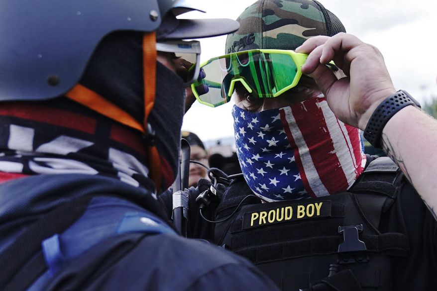 FILE - In this Sept. 26, 2020, file photo, member of the Proud Boys, right, stands in front of a counter protester as members of the Proud Boys and other right-wing demonstrators rally, in Portland. In its annual report set to be released Monday, Feb. 1, 2021, the Southern Poverty Law Center said it identified 838 active hate groups operating across the U.S. in 2020. (AP Photo/John Locher, File)