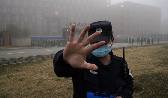 A security person moves journalists away from the Wuhan Institute of Virology after a World Health Organization team arrived for a field visit in Wuhan in China&#39;s Hubei province on Wednesday, Feb. 3, 2021. The WHO team is investigating the origins of the coronavirus pandemic has visited two disease control centers in the province. (AP Photo/Ng Han Guan)