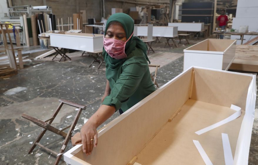 A worker assembles special coffins for the victims of COVID-19 at a factory in Tangerang, Indonesia, Tuesday, Feb. 2, 2021. The number of coronavirus-related cases and deaths in the world&#39;s fourth most populous country has been rising since early December, prompting several regional governments on the islands of Java and Bali to reimpose restrictions on public activity. (AP Photo/Tatan Syuflana)