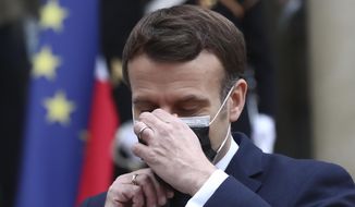 French President Emmanuel Macron takes off his face mask as he welcomes Serbian President Aleksandar Vucic for a working lunch at the Elysee Palace in Paris, Monday, Feb. 1, 2021. Serbian President Aleksandar Vucic is in Paris for bilateral talks with French President Emmanuel Macron. (AP Photo/Michel Euler)