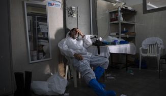 A worker from &amp;quot;Hevra Kadisha,&amp;quot; Israel&#39;s official Jewish burial society, dress in full protective gear rests at a special morgue for people who died from COVID-19, during a nationwide lockdown to curb the spread of the coronavirus, in the central Israeli city of Holon, near Tel Aviv, Israel, Sunday, Jan. 10, 2021. (AP Photo/Oded Balilty)