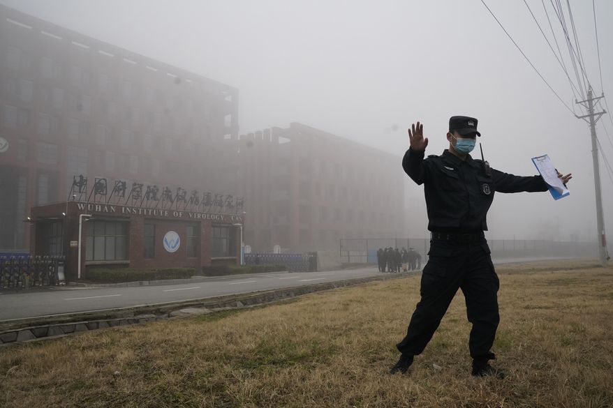 A security person moves journalists away from the Wuhan Institute of Virology after a World Health Organization team arrived for a field visit in Wuhan in China&#39;s Hubei province on Wednesday, Feb. 3, 2021. The WHO team is investigating the origins of the coronavirus pandemic has visited two disease control centers in the province. (AP Photo/Ng Han Guan)