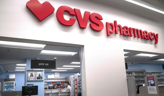 In this March 17, 2020, file photo, Pharmacist Evelyn Kim, wears a mask and gloves at the CVS pharmacy at Target in the Tenleytown area of Washington. The Biden administration will begin providing COVID-19 vaccines to U.S. pharmacies, including CVS, part of its plan to ramp up vaccinations as new and potentially more serious virus strains are starting to appear. (AP Photo/Carolyn Kaster) **FILE**