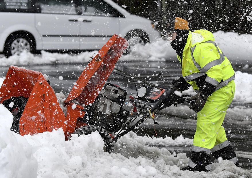 Mario Vieira, a custodian at the Beatrice H. Wood Elementary School in Plainville, Mass. struggles with a snowblower Tuesday, Feb. 2, 2021 while clearing sidewalks and walkways after the area received a blanket of wet, heavy snow overnight. (Mark Stockwell/The Sun Chronicle via AP)