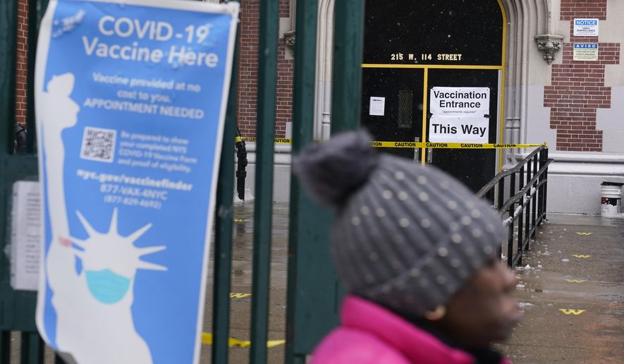 A woman walks past a closed COVID-19 vaccination site in New York, Tuesday, Feb. 2, 2021. The site was closed today due to the inclement weather. Coronavirus vaccination sites across the Northeastern U.S. are getting back up and running after a two-day snowstorm that also shut down public transport, closed schools and canceled flights. Some vaccination sites in New York City remained closed, but others, including those run by the public hospital system, were open Tuesday. (AP Photo/Seth Wenig)